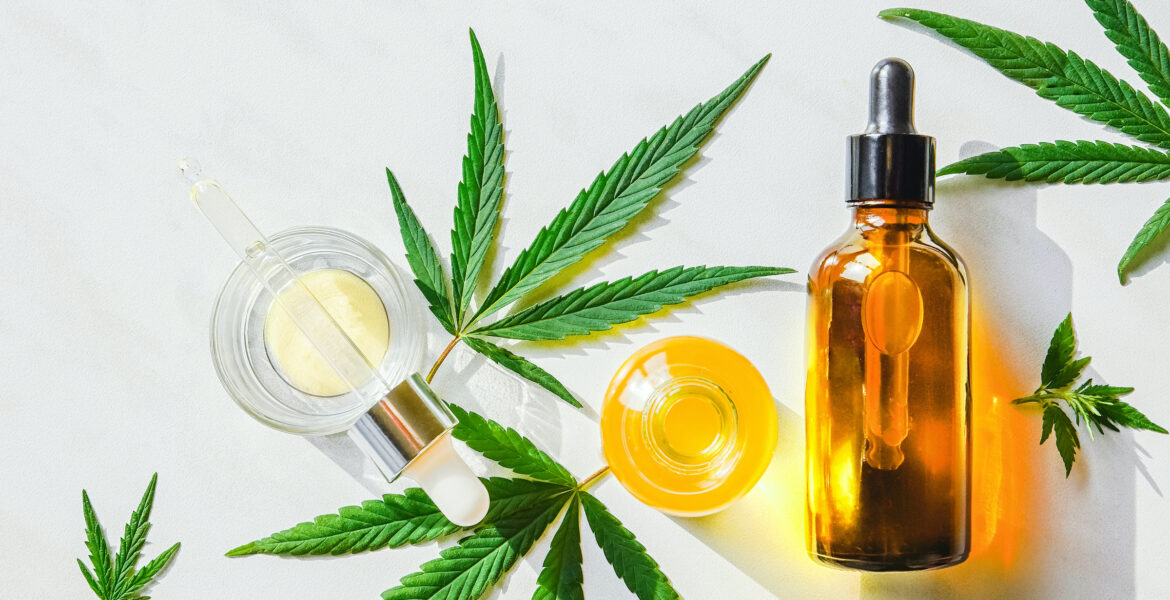 Glass brown bottle with cannabis CBD oil and hemp leaves on a marble background. Copy space